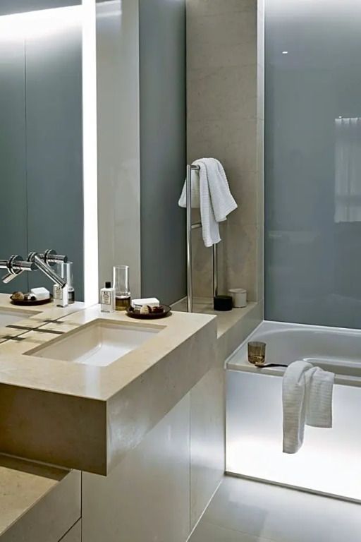 Modernes Badezimmer mit beiger Marmorwaschplatte und Badewanne.