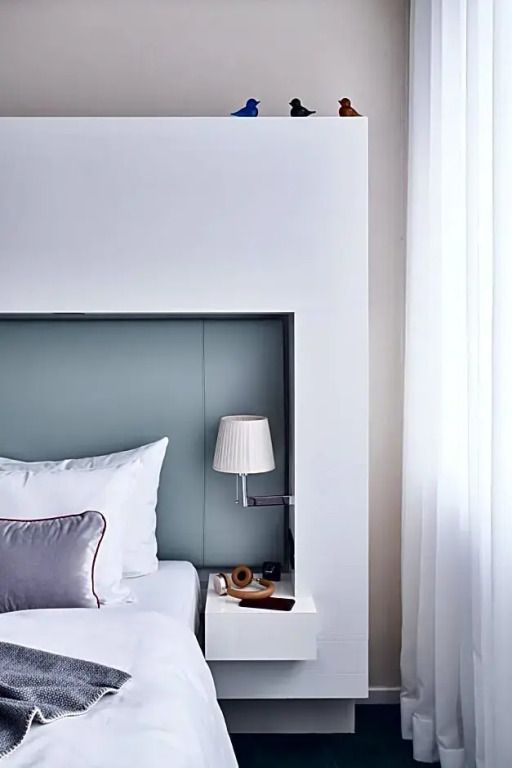 Detail eines Betts mit moderner Stehlampe und heller Wand