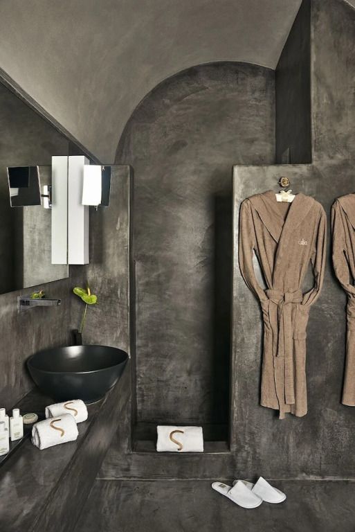 Luxuriöses Badezimmer mit dunklen Wänden und eleganten Bademänteln