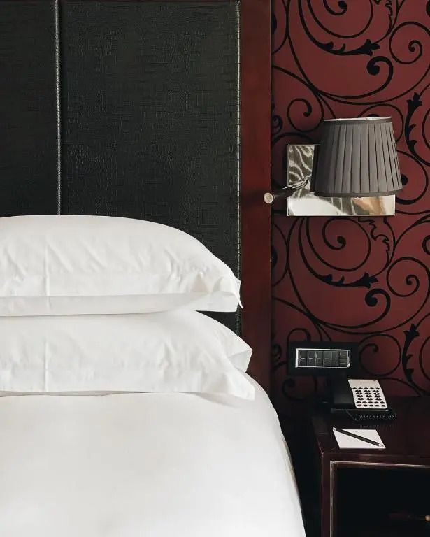Detailaufnahme eines eleganten Bettes mit hochwertiger Bettwäsche und dezenter Beleuchtung
