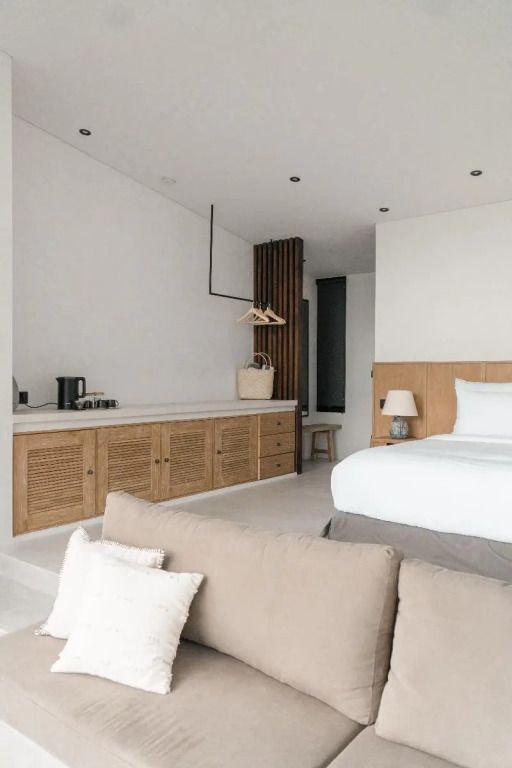 Elegantes Schlafzimmer mit Doppelbett, Sofa und Holzdetails in neutralen Tönen