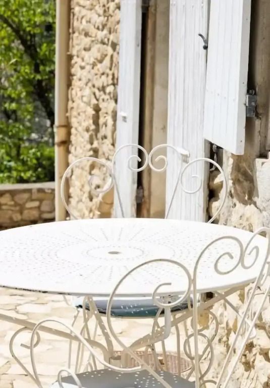 Weißer Metalltisch mit Stühlen auf einer Terrasse aus Stein