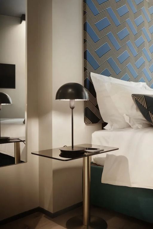 Moderne Nachttischlampe und stilvolles Kissen in einem Hotelzimmer.