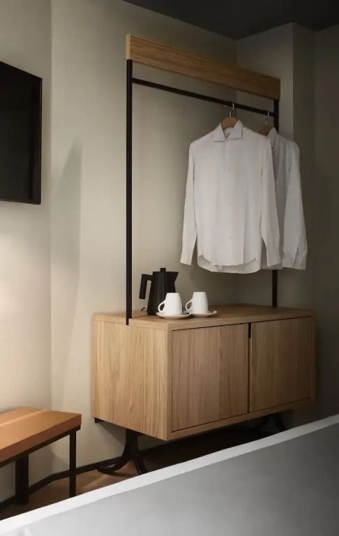 Schlichte Garderobe mit Hemden und Teeservice im Hotelzimmer.