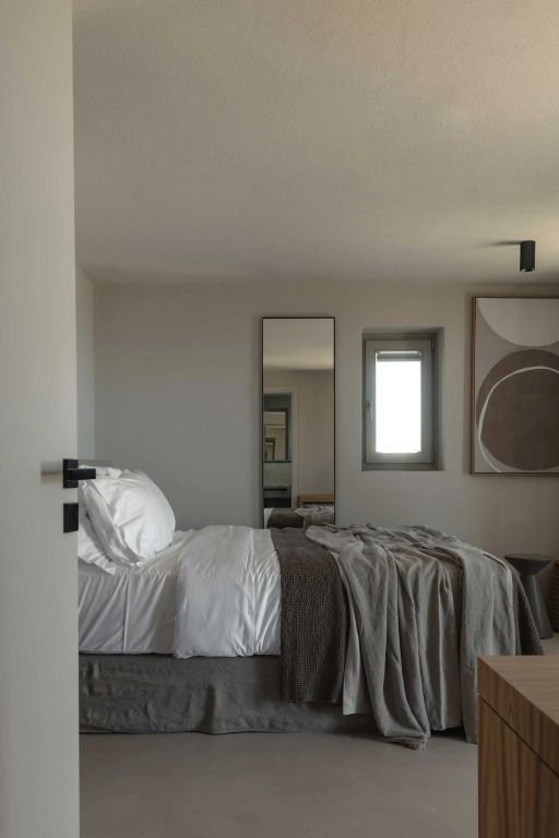 Modernes Hotelzimmer mit stilvollem Bett, Spiegel und Kunstwerk an der Wand