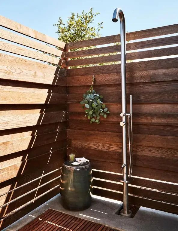 Outdoor Dusche mit Holzwänden und Pflanzen im Hintergrund