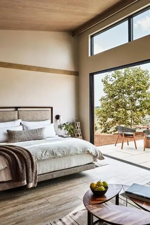 Helles Schlafzimmer mit großem Fenster und Blick auf die Terrasse