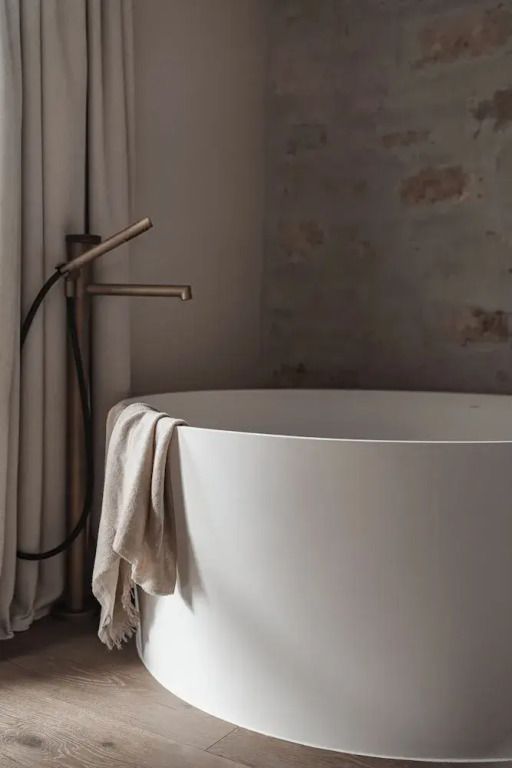 Freistehende Badewanne mit moderner Armatur und Leinentuch