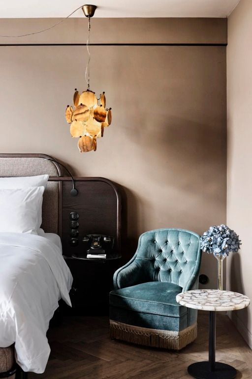 Elegantes Hotelzimmer mit Designer-Lampe und grüner Samtliege.