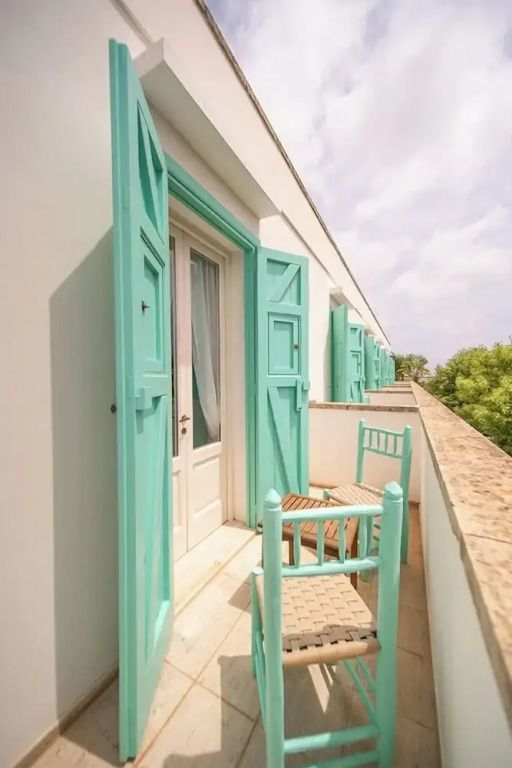 Balkon mit türkisfarbenen Türen und Blick auf die Natur