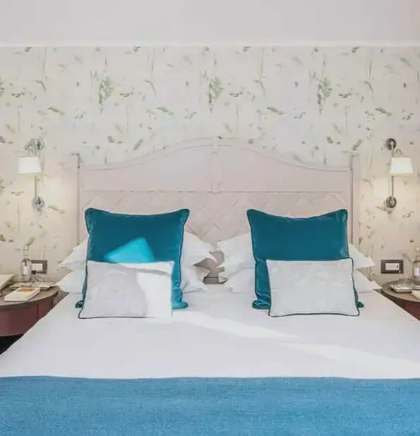Gemütliches Doppelbett mit blauen Kissen in eleganter Junior-Suite