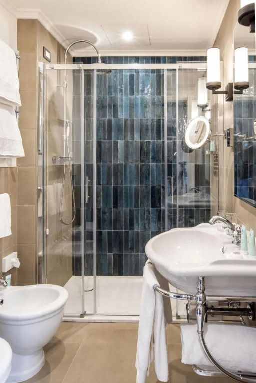 Modernes Badezimmer mit Glasdusche und blau gefliester Wand