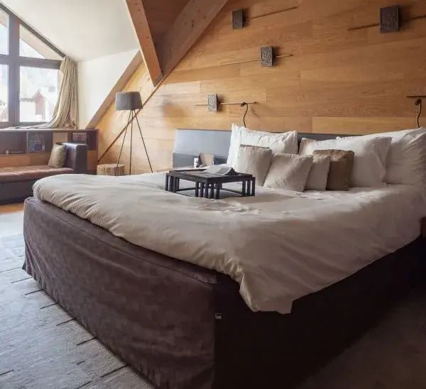 Luxus-Schlafzimmer der Furka Suite mit Holzverkleidung und großem Bett.