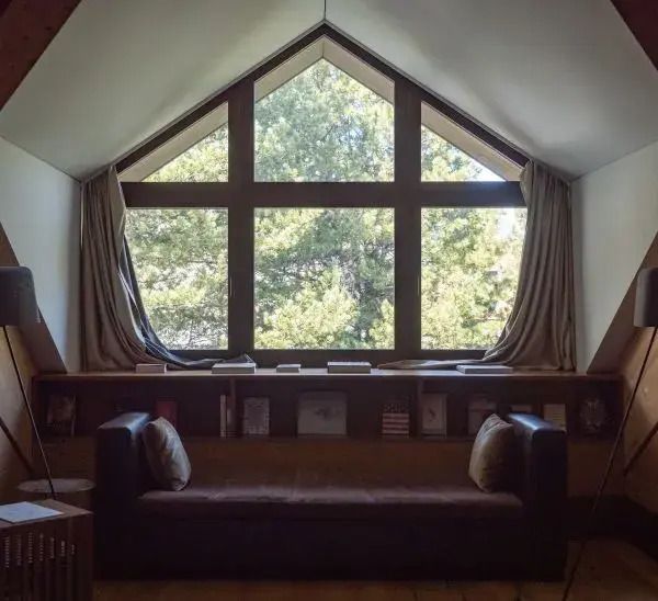 Panoramafenster mit Blick auf Wald und moderne Leseecke mit Sitzgelegenheit.