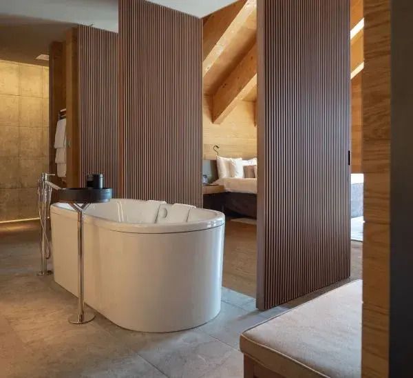 Offenes Badezimmer mit Badewanne in der Gemsstock Doppel Suite