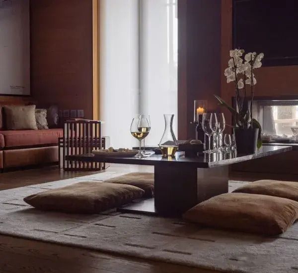 Gemütliche Sitzecke mit modernen Kissen und stilvollem Tisch vor einem Kamin im Chedi Andermatt