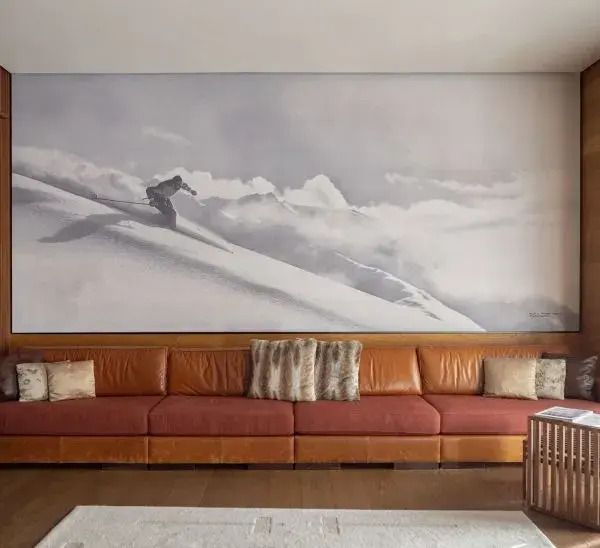 Stilvoller Raum mit großer Ledercouch und beeindruckendem Wandbild im Chedi Andermatt