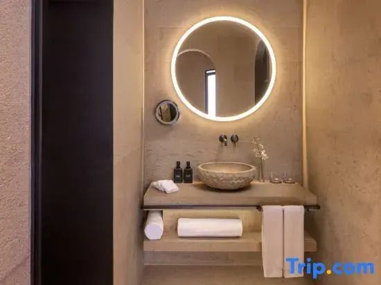 Modernes Badezimmer mit beleuchtetem runden Spiegel und stilvollem Waschbecken