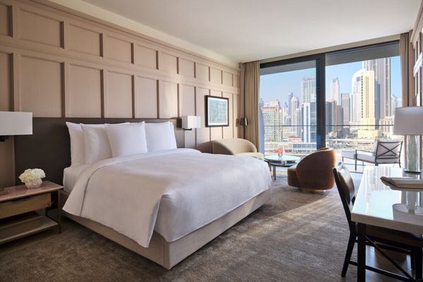 Helles Schlafzimmer mit Doppelbett und Stadtblick durch große Fenster