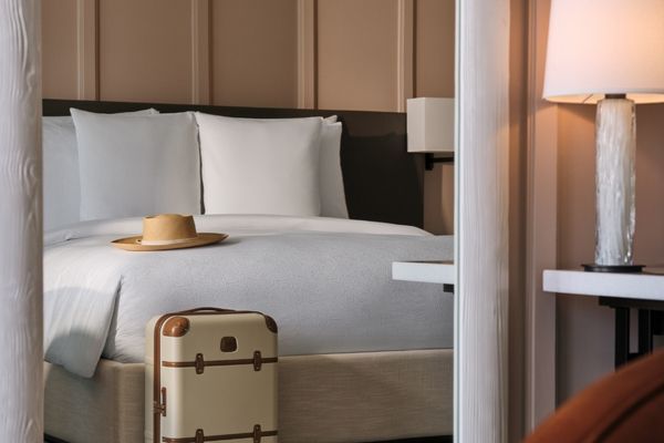 Doppelbett mit luxuriöser Bettwäsche und elegantem Koffer im Vordergrund