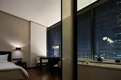 Abendliches Zimmerambiente mit stilvoller Beleuchtung und Sitzbereich neben Fenstern.