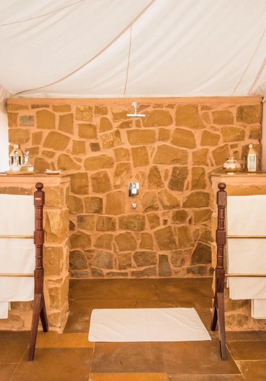 Zeltbadezimmer mit rustikaler Steinwand und Doppelwaschbecken