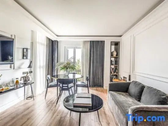 Helles Wohnzimmer mit grauem Sofa und Esstisch in der Suite des Hotels Serras Barcelona