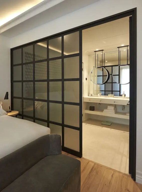 Badezimmer hinter einer Glaswand mit Doppelwaschbecken und modernen Armaturen