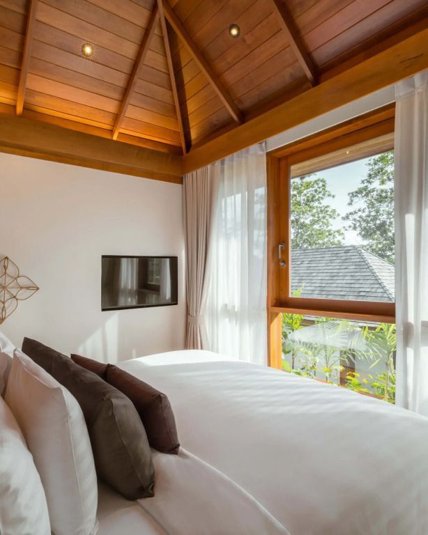 Helles Schlafzimmer mit offenem Fenster und exotischem Ausblick