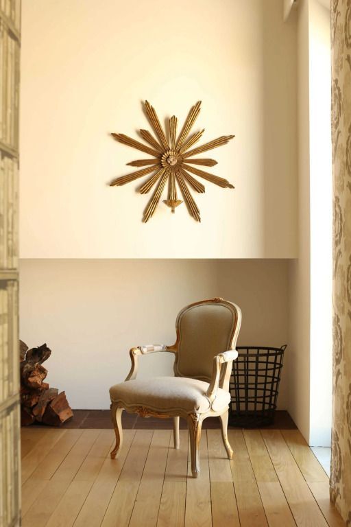 Luxuriöser Sessel unter goldener Wanddekoration in elegantem Ambiente