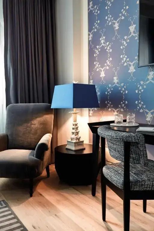 Gemütliche Sitzgelegenheit im Hotelzimmer mit blauer Lampe und stilvollem Dekor.