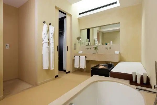 Modernes Badezimmer mit Badewanne und Bademänteln im Verdura Resort