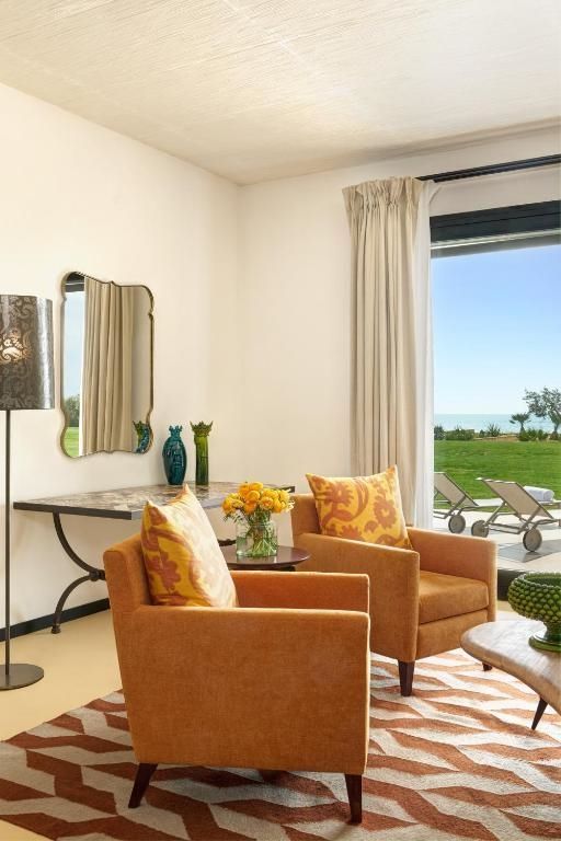 Sitzecke mit zwei Sesseln und Terrasse mit Blick auf den Garten und das Meer