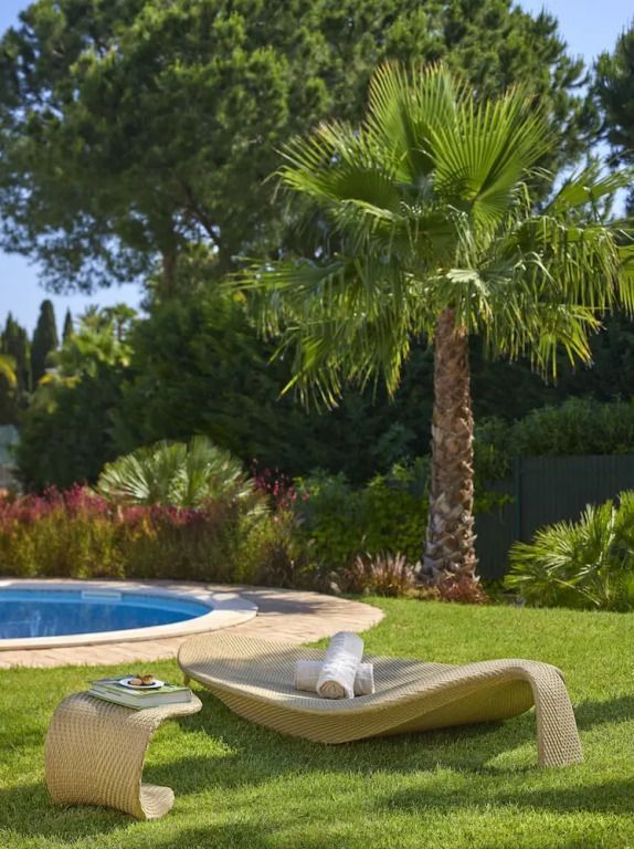 Entspannungsbereich am Pool mit Liegestuhl und Palmen