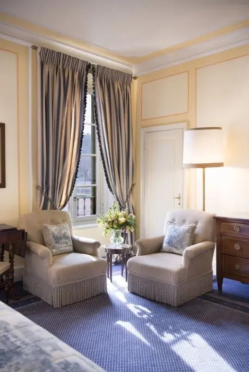 Sitzecke im klassischen Doppelzimmer mit eleganten Sesseln und Vorhängen.
