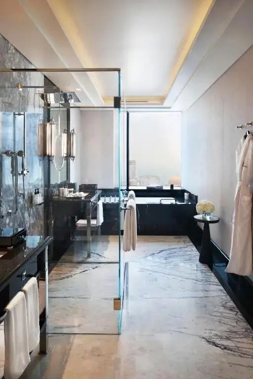Modernes Badezimmer mit verglaster Dusche und Marmorakzenten
