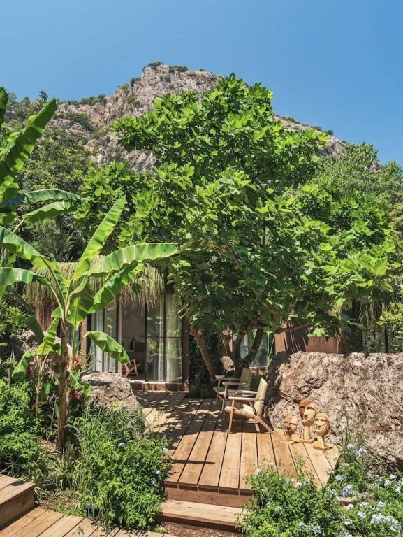 Holzterrasse im Gartenbereich des Deluxe Doppelzimmers umgeben von Felsen und Pflanzen