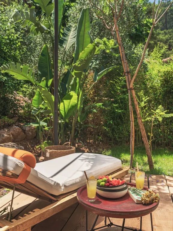 Sonnenliegen mit Obst und Getränken umgeben von üppigem Garten im Freien