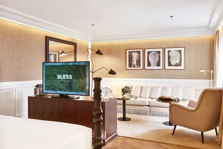 Wohnbereich einer Suite mit hellem Sofa, kleinen Beistelltischen und Fernseher auf dem Sideboard