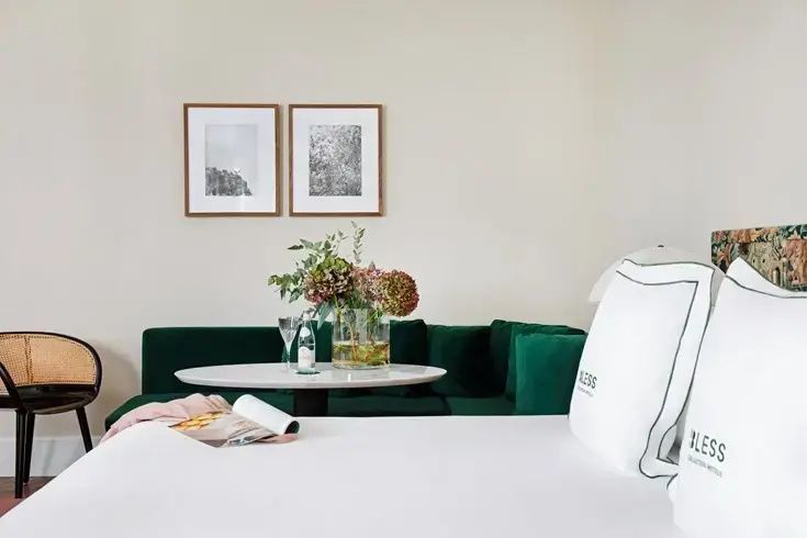 Nahaufnahme der Sitzecke im Zimmer mit grünem Samtsofa, Blumentopf auf dem Tisch und Wandbildern.