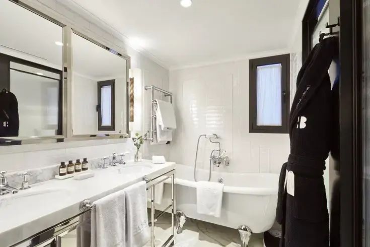 Hell gefliestes Badezimmer mit freistehender Badewanne, Doppelwaschtisch und Handtuchhalter