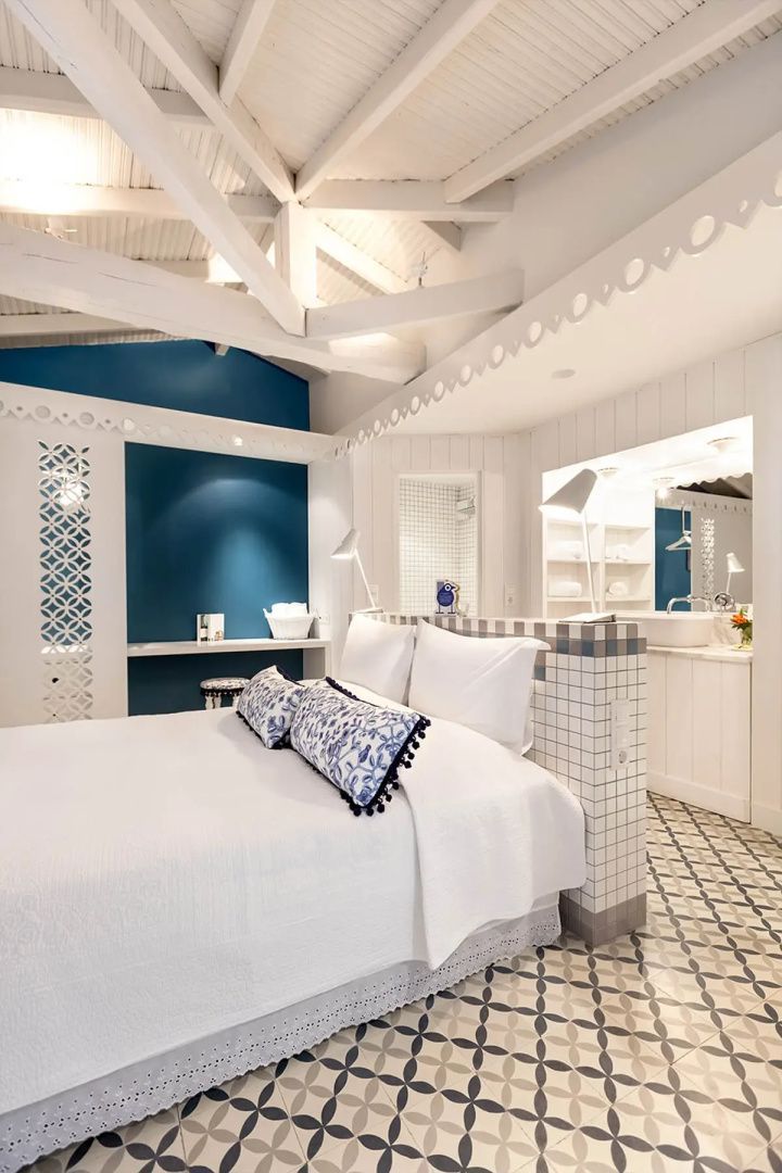 Hotelzimmer mit holzverkleideter Decke, weißem Doppelbett und blauer Wandgestaltung.