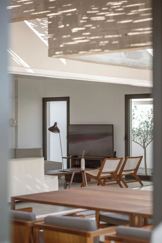 Heller Wohnbereich mit Fernseher, Holzstühlen und Couchtisch in einer modernen Suite.