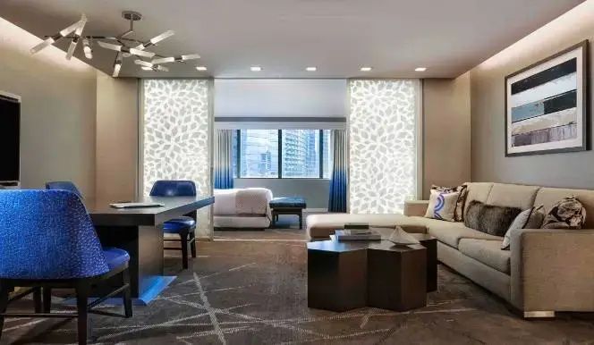 Wohnbereich einer Suite mit Eckcouch, Couchtisch und Blick auf das angrenzende Schlafzimmer.
