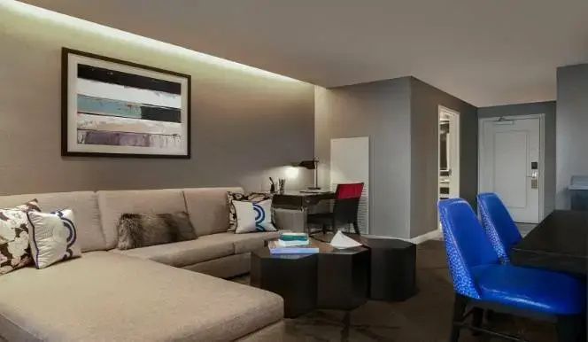 Wohnbereich mit hellem Ecksofa, Schreibtisch und Wandbild in neutralen Farbtönen.