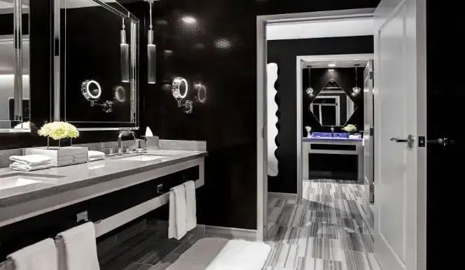 Badezimmer mit dunklen Wänden, doppeltem Waschtisch, Spiegeln und gestreiftem Fliesenboden.