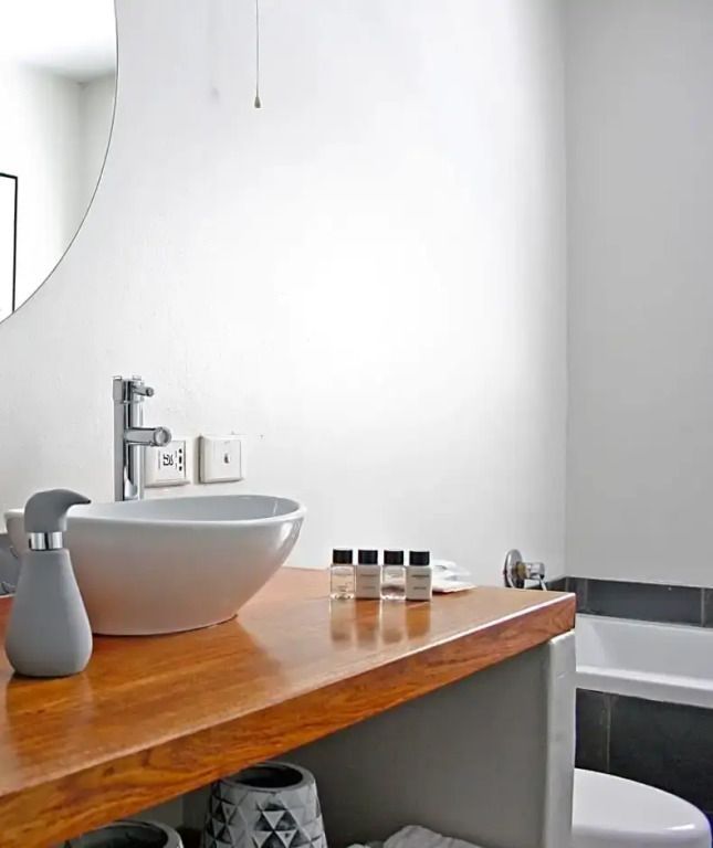 Modernes Badezimmer mit Waschbecken auf Holzablage und Pflegeprodukten