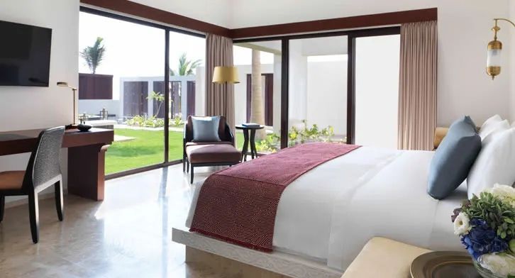 Helles Schlafzimmer in einer Villa mit großem Bett und Blick auf den Garten durch Glaswände