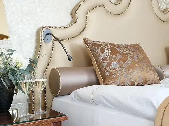 Stilvolles Doppelbett mit prunkvollen Kissen und Champagnergläsern