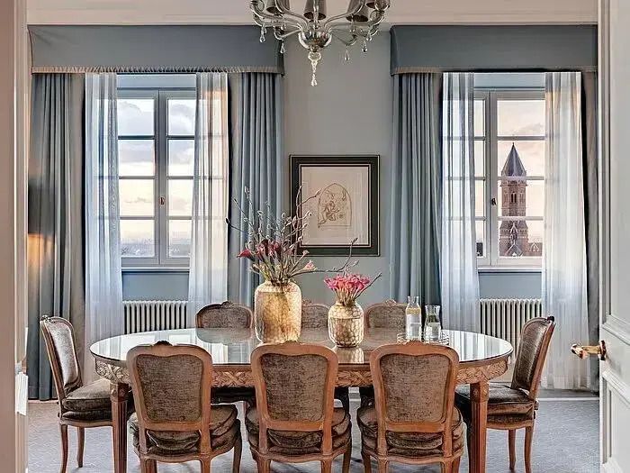 Hochwertig gestalteter Essbereich in der Suite mit Tisch und Stühlen vor großen Fenstern.